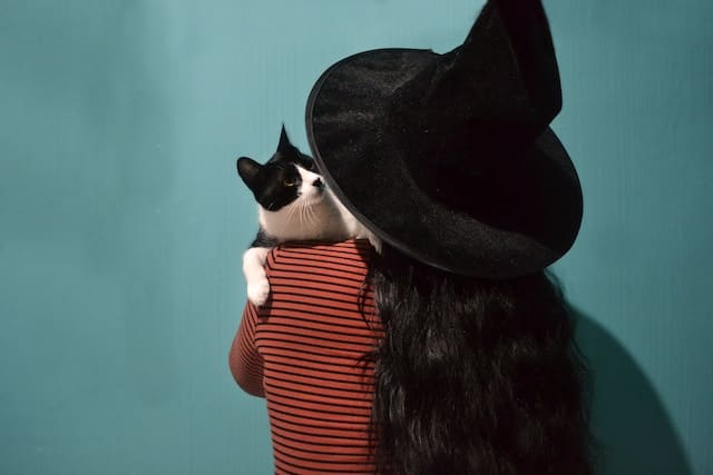 Chat sur l'épaule d'une femme avec un chapeau de sorcière