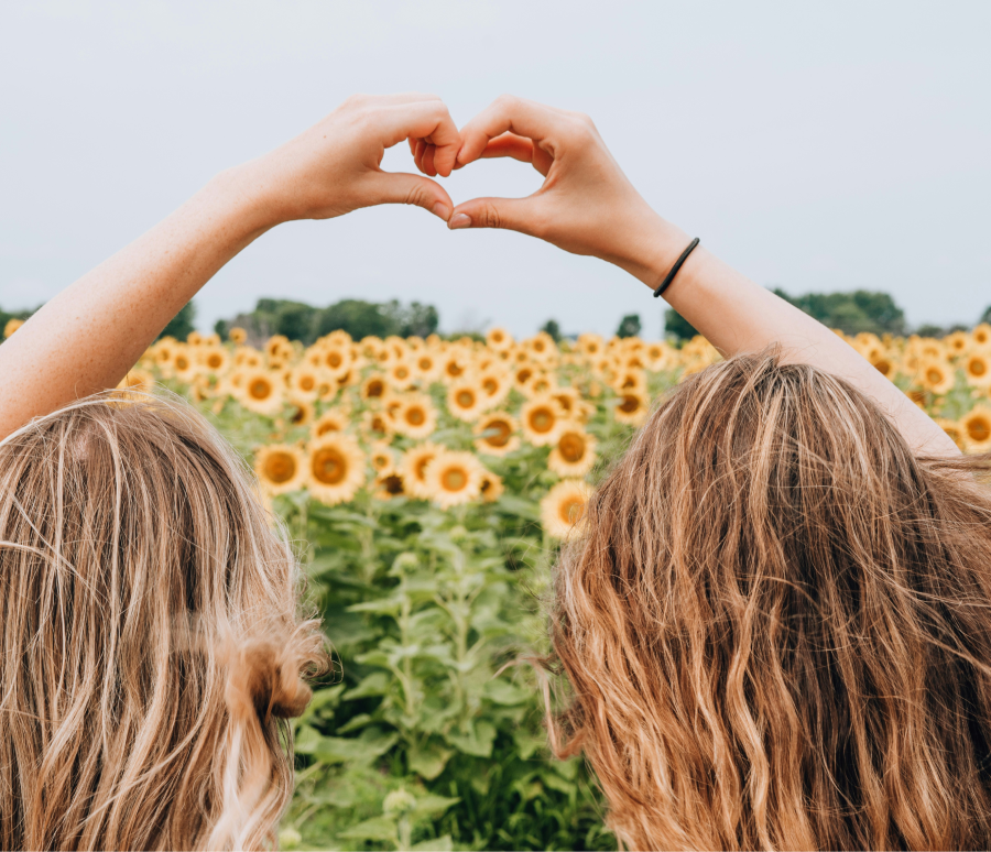 Deux femmes dans un champ qui font un coeur avec leurs mains